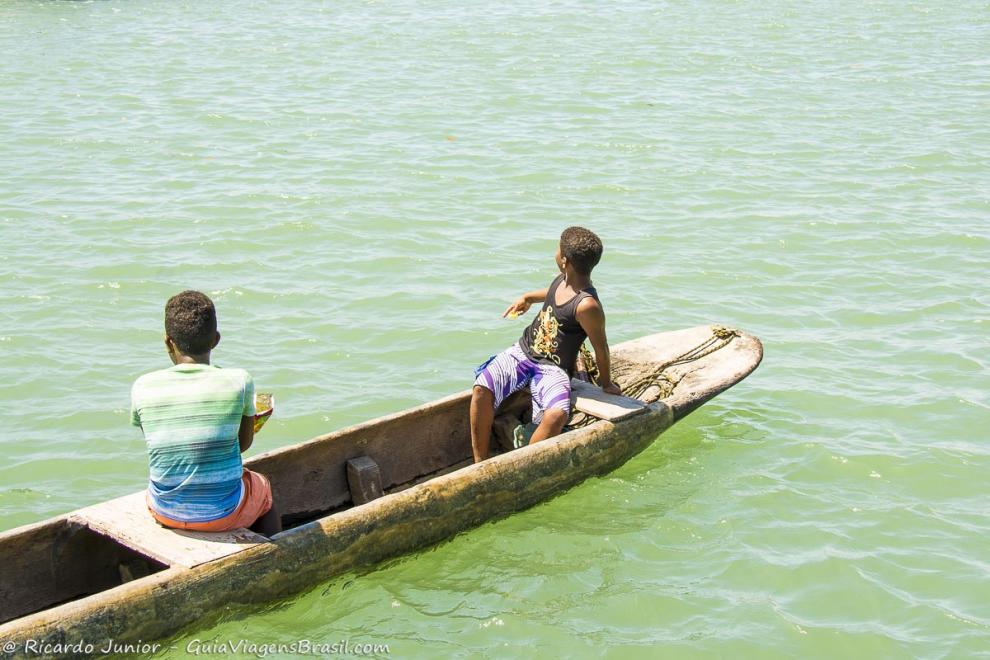 Imagem duas crianças em um pequeno barco de madeira na Ilha de Boipeba.